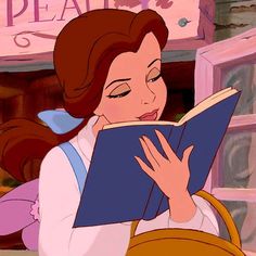 a woman reading a book in front of a sign that reads beauty and the beast