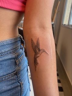 a woman's arm with a hummingbird tattoo on the back of her left arm