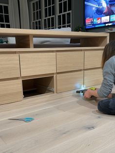 a young boy is playing with toys on the floor in front of a flat screen tv