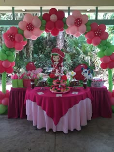 the table is set up with pink and green balloons, flowers, and other decorations