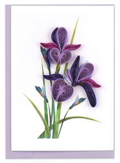 three purple flowers with green stems on a white background, one is cut from paper and the other is made out of cardboard