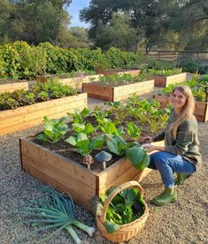 a woman kneeling down in front of a garden filled with lots of plants and vegetables