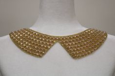 a white mannequin with gold beading on it's chest and collar