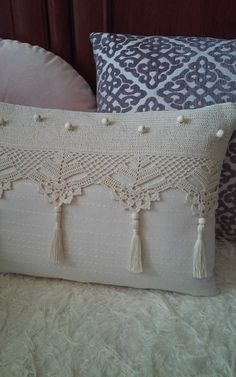 two pillows with tassels on them sitting on a bed