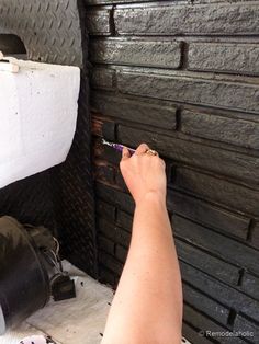 a person using a toothbrush to brush their teeth in front of a brick wall