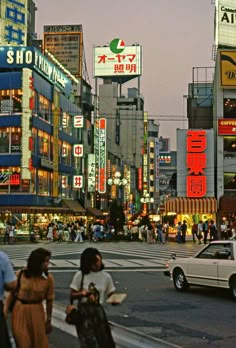 a busy city street filled with lots of traffic and people walking across the crosswalk