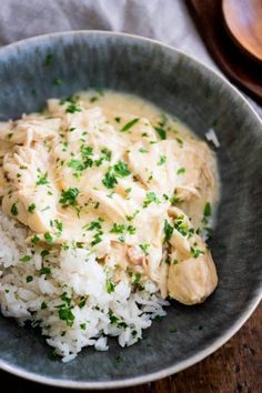 a bowl filled with rice and chicken covered in gravy on top of a wooden table