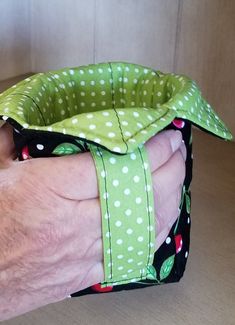 a person's hand with a green and white polka dot covered ring on it