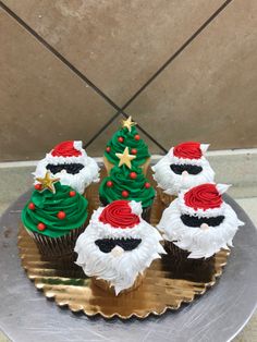 cupcakes decorated like santa claus and christmas trees on a silver platter with gold trim