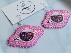 the earrings are decorated with beading and space imagery on them, as well as an advert for arkknow