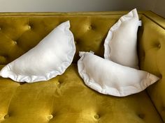 two white pillows sitting on top of a green couch