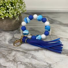 a blue and white beaded bracelet with tassels on a marble counter top