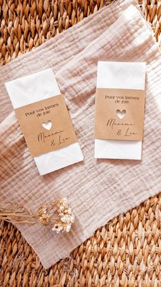 two pieces of paper with hearts on them sitting on top of a woven table cloth