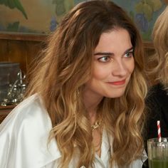 two women sitting next to each other at a table with drinks in front of them