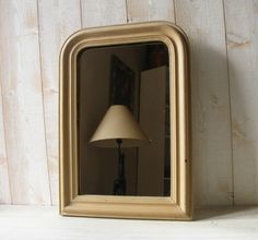 a lamp sitting on top of a white shelf next to a mirror and wooden wall