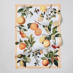 an orange and lemon print scarf on a white tablecloth with leaves, flowers, and fruit