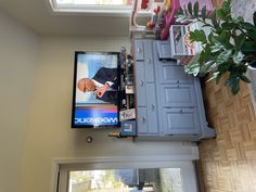 a flat screen tv mounted to the side of a wall next to a potted plant