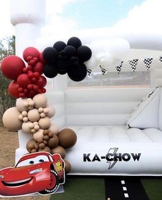 an inflatable balloon arch with cars and balloons attached to it, along with other decorations