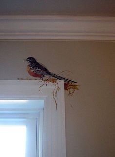 a bird sitting on top of a window sill next to a white door frame