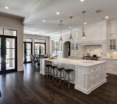 a large open kitchen with white cabinets and wood flooring is pictured in this image