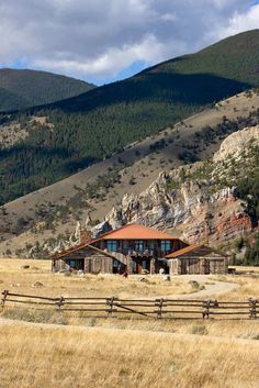 a house in the middle of a field with mountains in the background