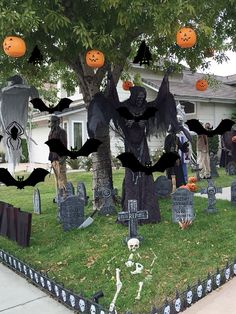 halloween decorations in front of a house with bats and pumpkins hanging from the trees