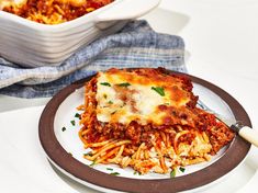 a white plate topped with lasagna next to a casserole dish filled with pasta