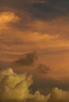 the airplane is flying high in the sky with clouds behind it and another plane on the ground