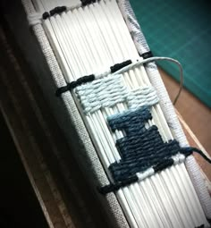 a close up of an object made out of white and blue yarn with black thread