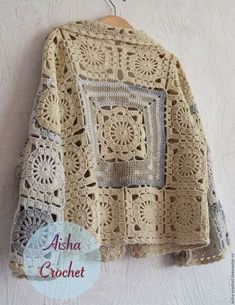 a crocheted jacket hanging on a wall next to a wooden hanger with the name asha crochet