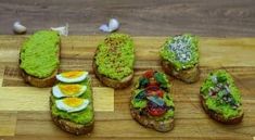 several pieces of bread with different types of food on them sitting on a cutting board