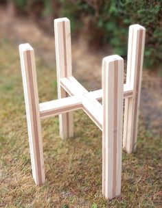 a small wooden chair sitting on top of a grass covered field next to a bush