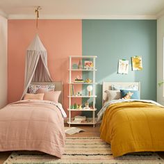 two beds in a bedroom with pink and blue walls