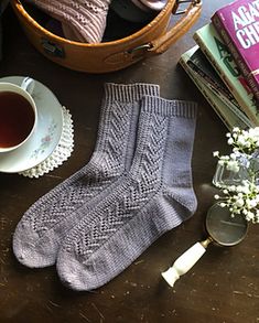 a pair of socks sitting on top of a wooden table next to a cup of tea