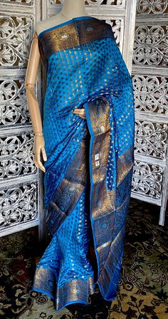 A High Quality Beautiful Peacock Teal Blue Color Handloom Pure Dupion Silk Banarasi Saree with Antique gold Zari Jaal Brocade all over. The entire saree has delicate Gold zari work. It has a gold Zari border and heavy brocade Pallu. A classic traditional Banarasi saree for all wedding celebrations. The saree comes with unstitch attached blouse. In comparison to other silk fabrics, dupion silk fabric is a bit strong because of its dual thread nature. In addition to being the most durable natural Peacock Teal, Silk Banarasi Saree, Blue Antique, Teal Blue Color, Beautiful Peacock, Silk Fabrics, Dupion Silk, Banarasi Saree, Zari Work