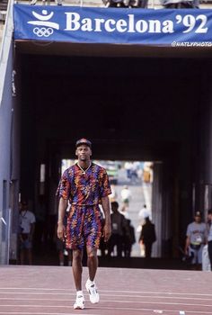 a man in a colorful shirt and shorts walking on a track