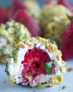 some strawberries and other food items on a white surface with one bite taken out