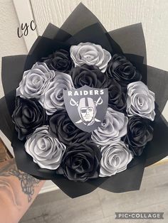 a bouquet of black and white roses with oakland football logo on the center, in front of a door