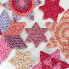 several crocheted stars are arranged on a white surface, one is pink and the other is purple