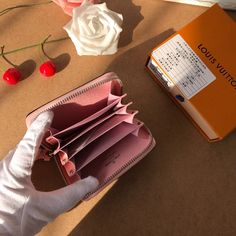 a person's hand holding an open wallet next to a calendar and flowers on a table