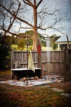 an old fashioned bathtub in the middle of a yard next to a large tree