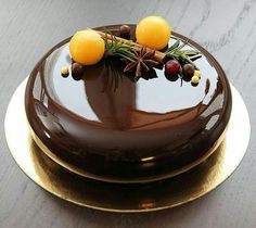 a chocolate cake topped with oranges and berries on top of a gold plated platter