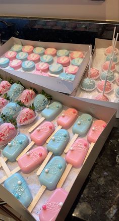 two boxes filled with pink and blue decorated cookies next to each other on top of a table