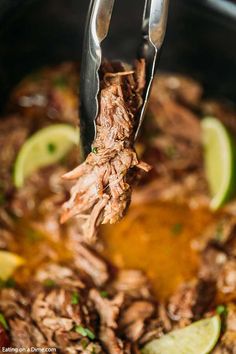 the meat is being cooked in the slow cooker with tongs and lime wedges