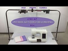 a white sewing machine sitting on top of a table next to a purple sign that says cheap overhead video recording rig