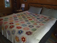 a bed with a quilt on top of it in a bedroom next to a window