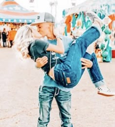 a man and woman kissing in front of an amusement park