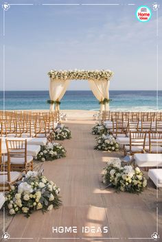 an outdoor ceremony setup with white flowers and greenery on the aisle leading to the beach