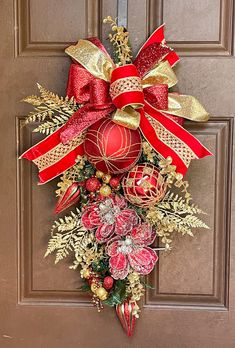 a red and gold christmas ornament hanging on the front door with decorations around it