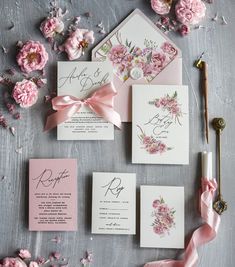 the wedding stationery is laid out with pink flowers and ribbon on top of it